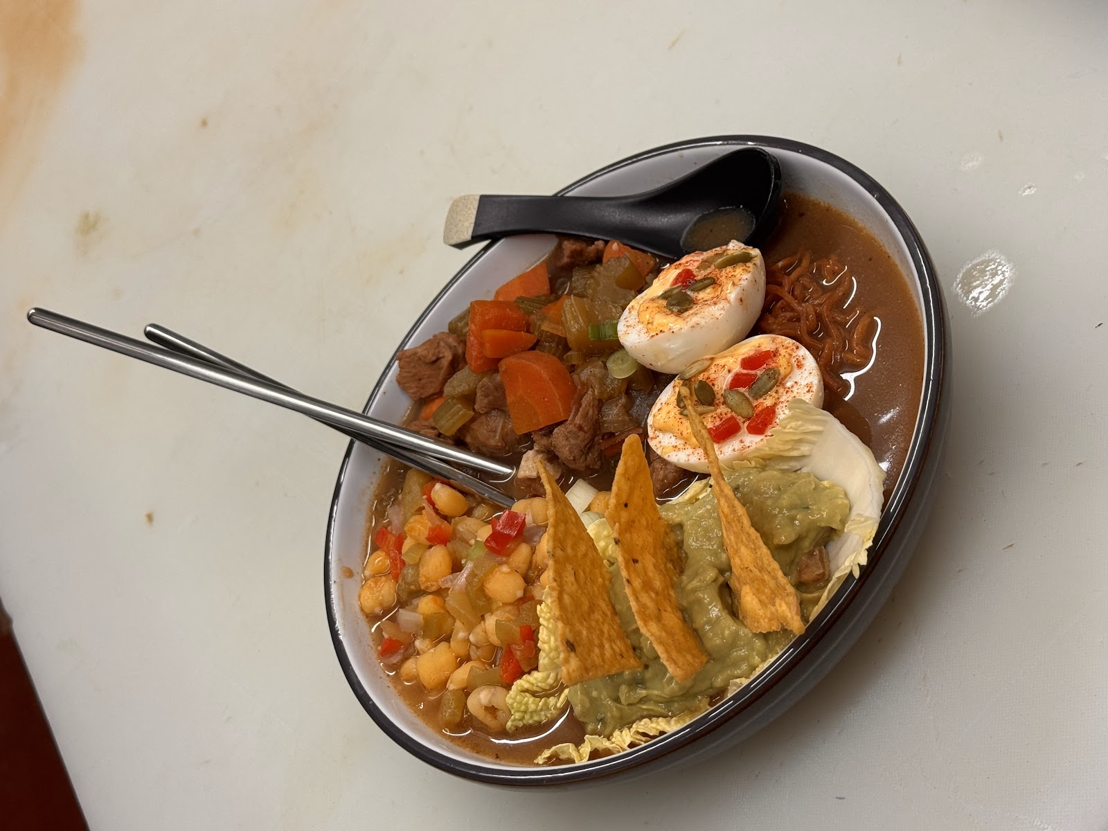 Fusion ramen bowl with tortilla chips, guacamole, seasoned egg and beef